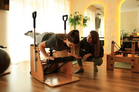 Woman practicing classical Pilates with her instructor
