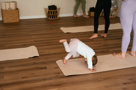 Toddler girl playing yoga on a mat