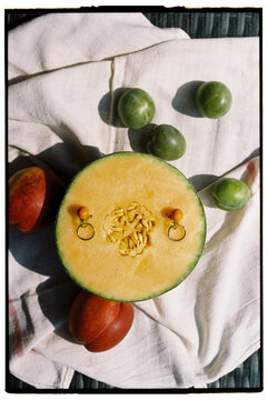 A still life with fruits melon, peach, and plums &mdash; with earrings