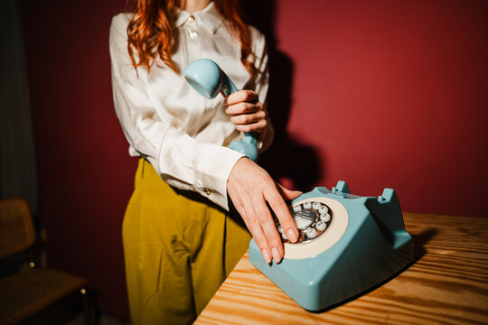 Woman dials a vintage telephone
