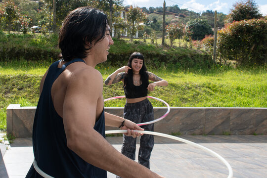 Couple Practicing Hula Hooping in a Sunny Outdoor Setting