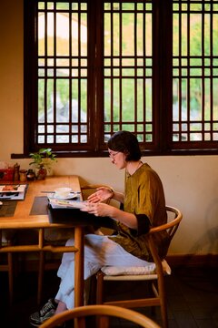Person Enjoying Food and Reading Menu in a Cozy Restaurant Setting