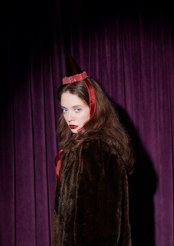 Portrait woman in fur coat wearing red festive party hat