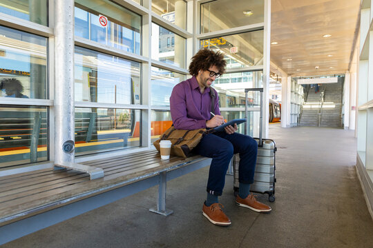 Man tablet computer stylus pen train station sitting
