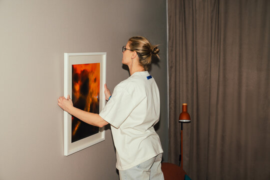 Woman Adjusting Picture Frame on Wall