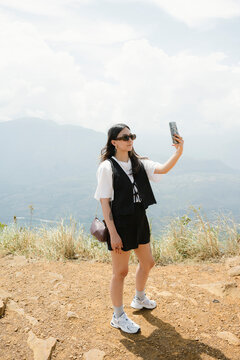 Woman taking selfie on mountain viewpoint during travel