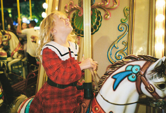 Girl Enjoys Time on Carousel Ride at the Fairground in Evening
