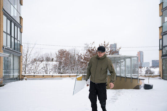 Man Carrying Glass Panel in Snowy Outdoor Area During Winter