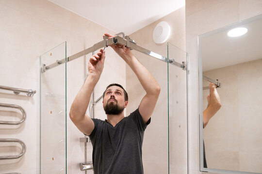 Man Installs Shower Door Frame in Bathroom Setting