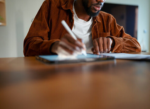 Man writes notes at a wooden table
