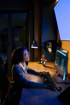 Young woman works late at night at desk
