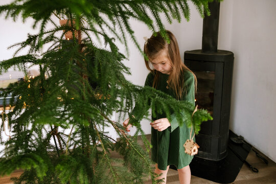 The girl is decorating the Christmas tree.