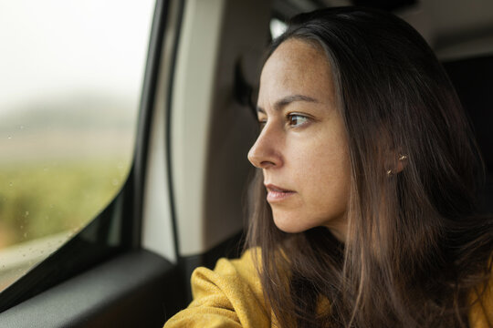 Close-up portrait of woman looking out car window