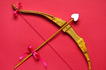 Naklejka premium Golden cupid's bow with arrow on red background. Valentine's Day celebration