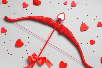 Naklejka premium Composition with red cupid's bow and paper hearts on grey background. Valentine's Day celebration
