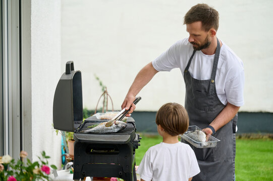 Father and Son Grilling Fresh Fish Outdoors