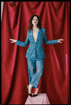 Woman balancing on pedestal in lace suit