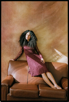 Woman reclining on leather sofa in studio