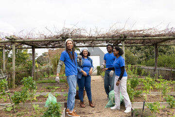African American volunteers wearing blue tees working in community garden with gloves