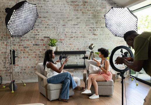Two armchairs facing each other are framing podcast microphones on stands in living-room studio