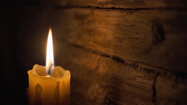 A single lit candle on a wooden table celebrating winter solstice with warm golden light