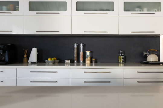 Modern kitchen counter featuring coffee machine, citrus bowl, canisters, oil and kettle