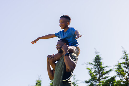 African American father and son playing at park, father carrying son on shoulders with wristwatch