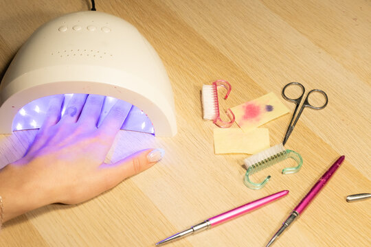 Hand under UV light for nail curing at manicure station