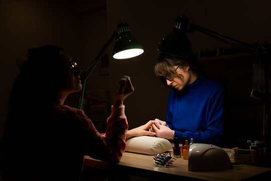 Manicure session in low light with two people present