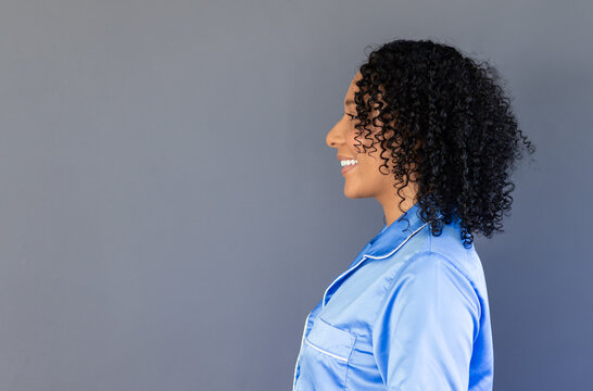 African American woman standing smiling facing right in studio wearing light blue shirt, copy space