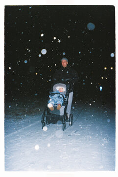 Parent walking with stroller in snowfall at night