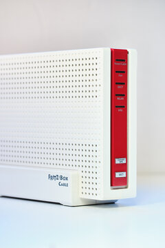 FritzBox 6591 cable on plain table, showcasing perforated design, red accents, Fritz logo. Modern networking device with clean lines and ventilation slits against neutral background