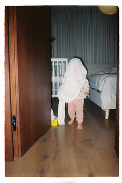 Toddler hiding under bedsheet and walking at home -  - film analog