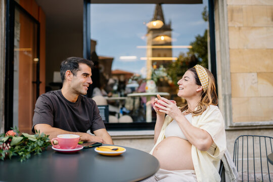 Expecting couple having coffee date in city cafe