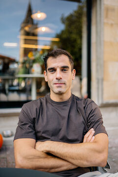 Man looking at camera with arms crossed in city