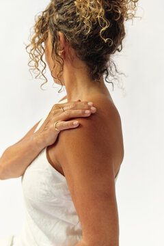 Profile portrait of a woman massaging her shoulder