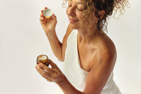 Woman opening and smelling a cosmetic cream