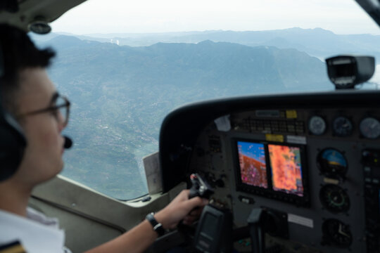 Cockpit view showing a pilot and mountains in the background.