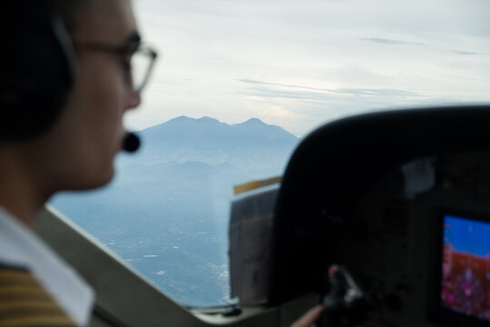 Cockpit view showing a pilot and mountains in the background.