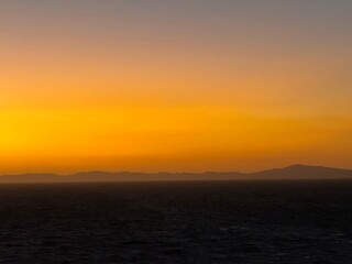 Fototapeta premium Breathtaking stunning sunrise over the ocean near Roatan, Honduras before an intense storm. Stunning orange and yellow colors meet the sea waves. Mountains in the distance.
