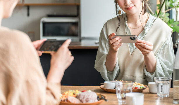 A woman taking photos of food on her smartphone while visiting cafes