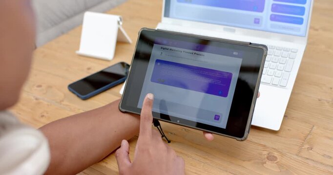 Left hand is placing tablet on tripod on desk; finger is swiping to reveal app content