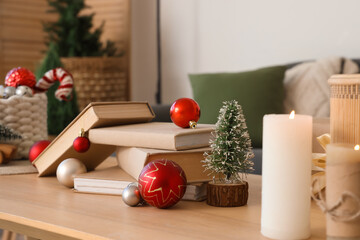 Books with Christmas balls and fir tree on table in living room