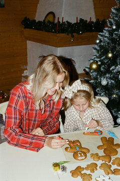 Mother and Daughter Decorating Gingerbread Cookies at Home
