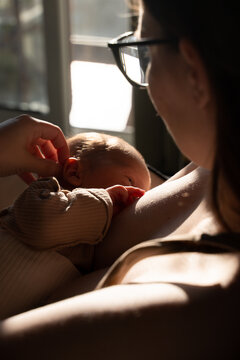 Mother breastfeeding newborn baby at home