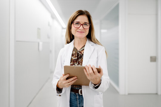 Female doctor smiling while holding medical records
