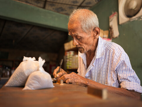 Elderly shopkeeper tallies sale in small spice shop in Sri Lanka