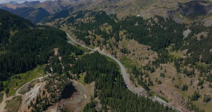 Aerial of serpentine alpine roadway by forested mountain slopes, Million Dollay Highway Colorado USA