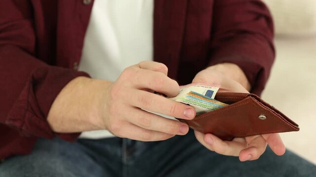 Man counting euro banknotes in wallet against blurred background, closeup