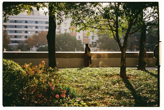 Young woman standing in a city park near trees and flowers